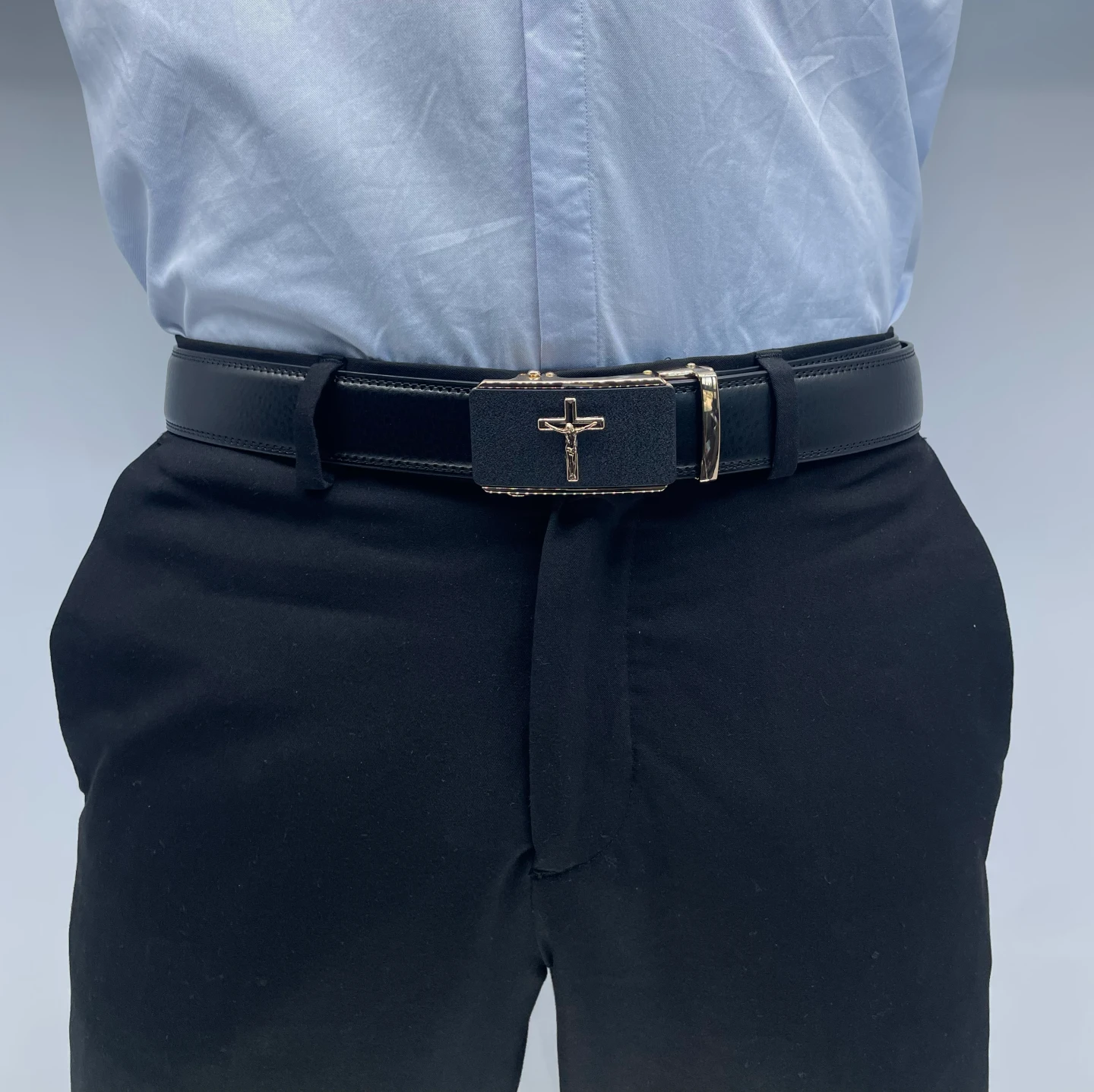 Mise en situation de la ceinture Jesus sur un pantalon habillé, illustrant son élégance et sa symbolique.